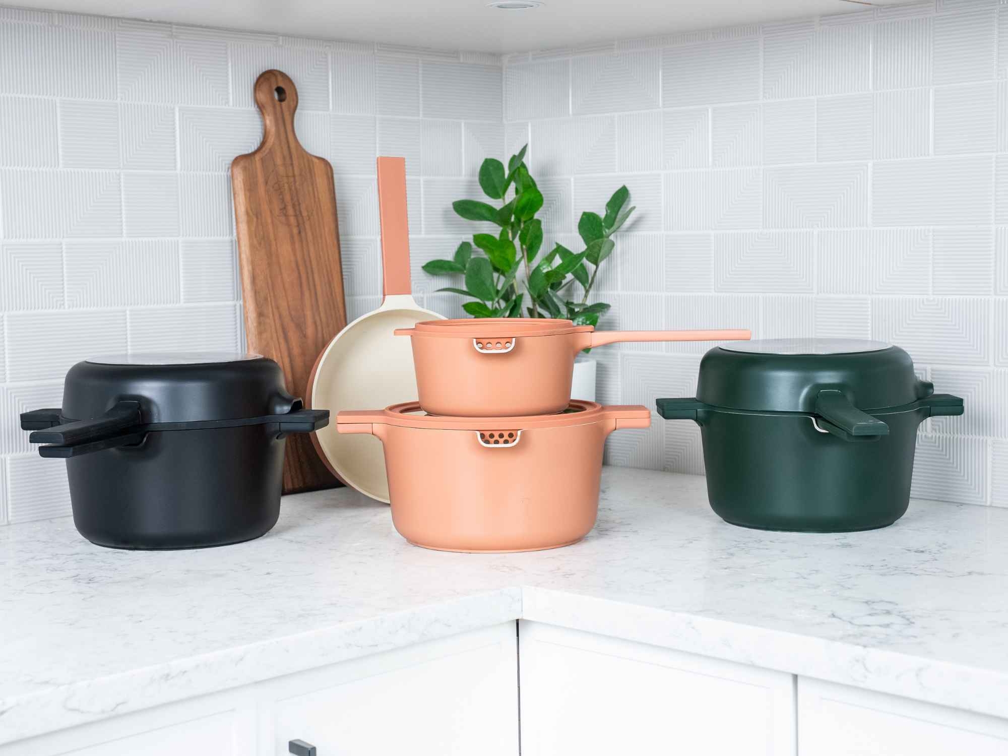 The Alva Neat nesting set shown in Black, Peach and Green, each stacked into a single compact stack on a marble kitchen counter