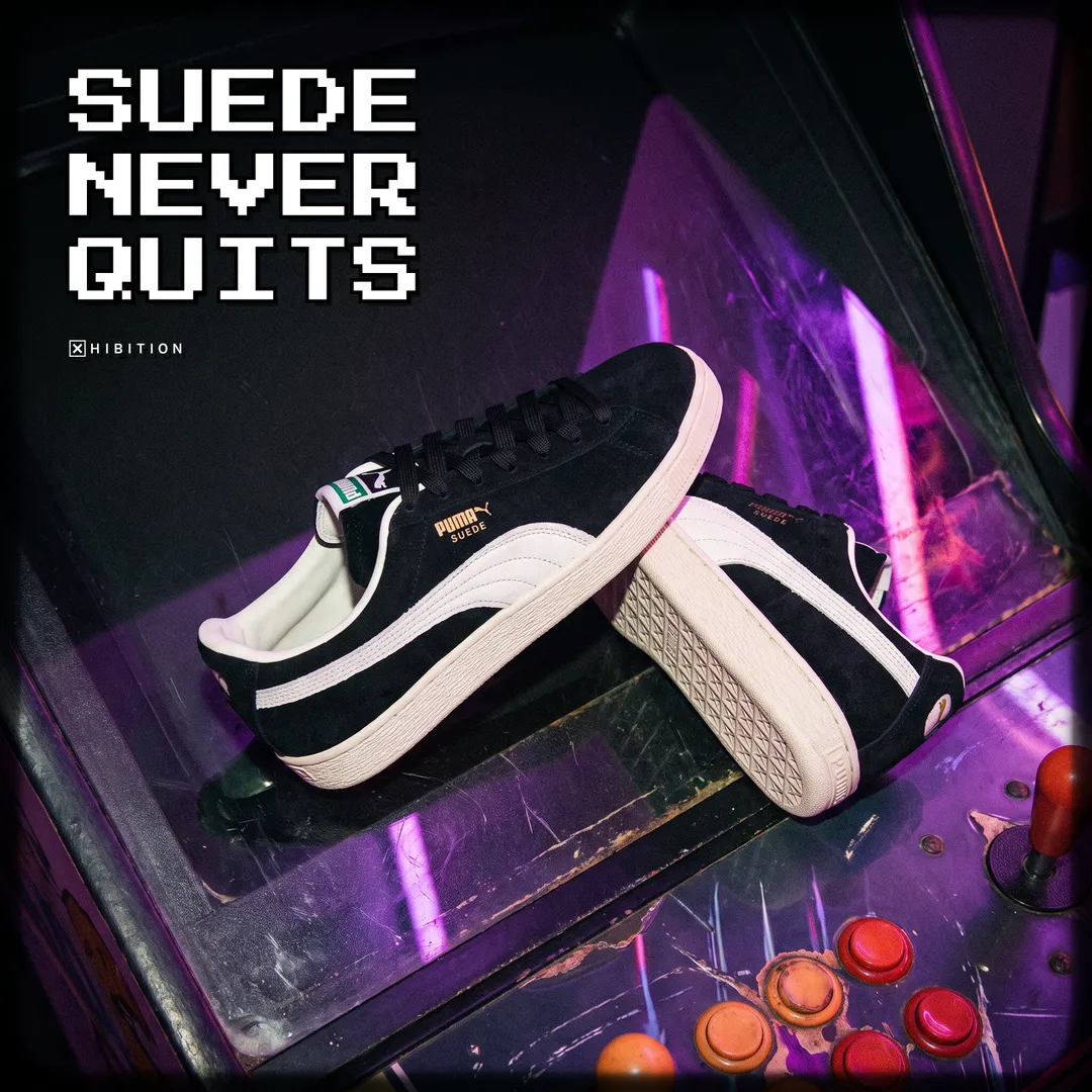 PUMA Suede Charles F. Stead I sneakers propped on an arcade cabinet under purple neon, showing the cream rubber foxing sole and the patterned outsole tread.